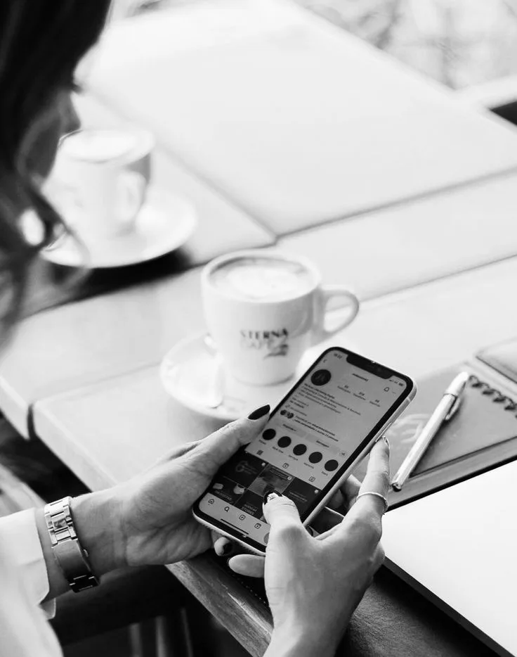 Mani con smartphone e caffè: gestione dei social media